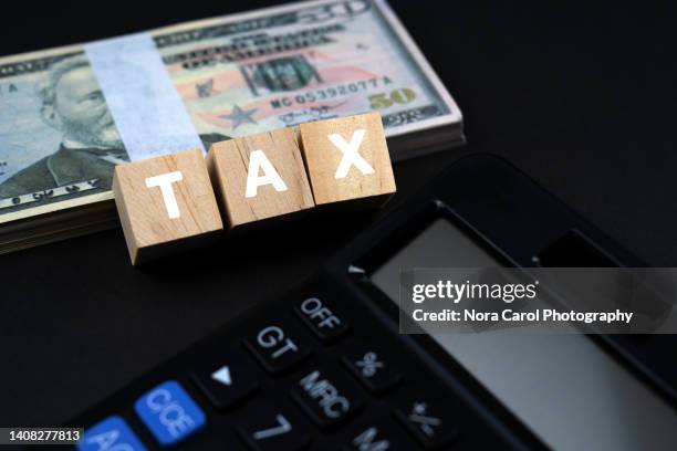 tax text on wood block with 50 american dollar and calculator - government accountability office stock pictures, royalty-free photos & images