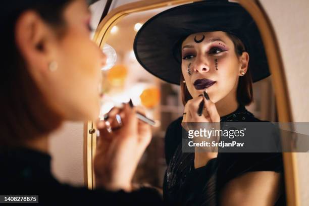 junge kaukasische frau, die make-up für halloween-party macht - halloween party stock-fotos und bilder