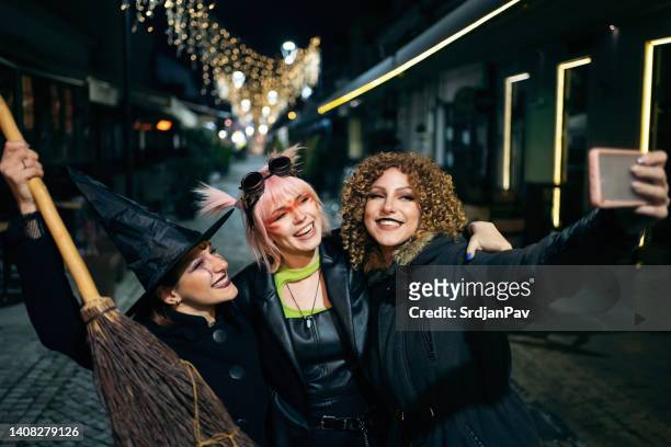 three young women in haloween costumes making selfies on the city street - halloween party 個照片及圖片檔