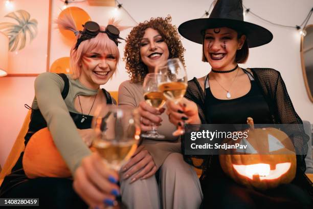 three young caucasian women in halloween costumes drinking wine and having fun together - halloween toast stock pictures, royalty-free photos & images