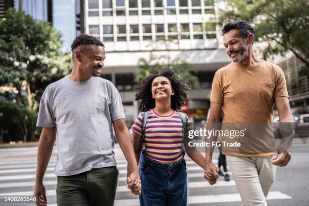happy and pride girl crossing street with her two fathers - couple crossing street stock pictures, royalty-free photos & images