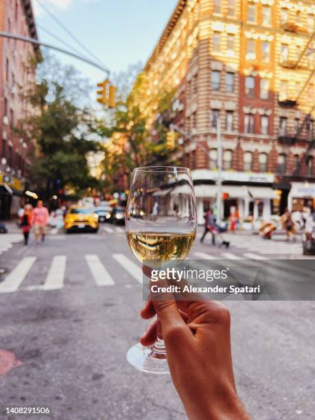 man drinking a glass of white wine on the street in new york city, usa - new york food stockfoto's en -beelden
