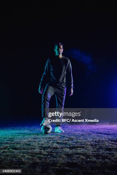 soccer player relaxes in illuminated field, at night - football player standing stock pictures, royalty-free photos & images