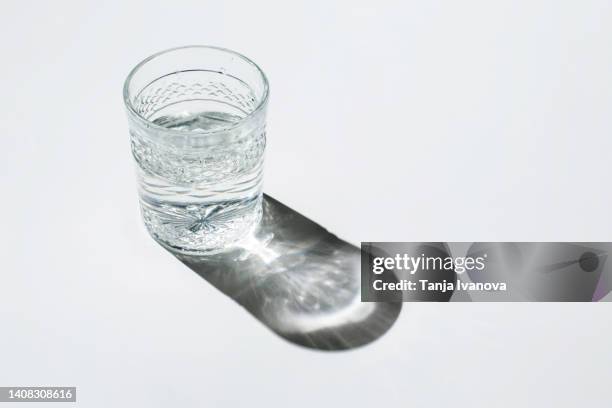 glass glass with water on white background - glass shadow stockfoto's en -beelden