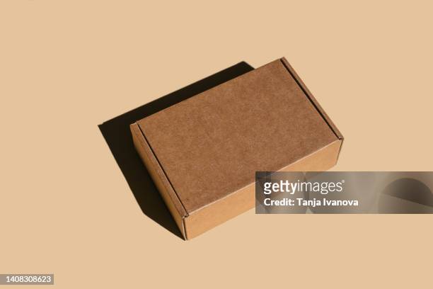 brown cardboard box on beige background. - cardboard box foto e immagini stock