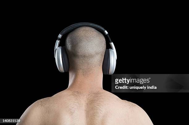 rear view of a man listening to headphones - hinterkopf stock-fotos und bilder