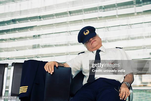pilot resting on a bench at an airport - man sleeping with cap stock pictures, royalty-free photos & images