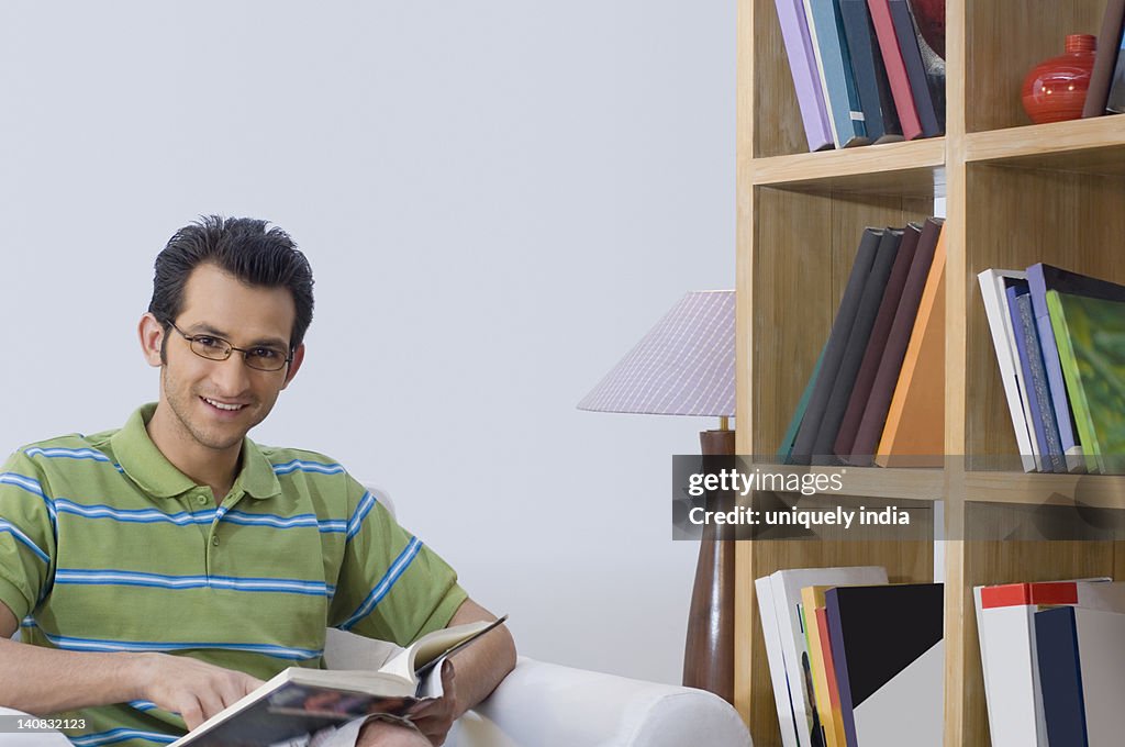 Portrait of a man reading a book in an armchair