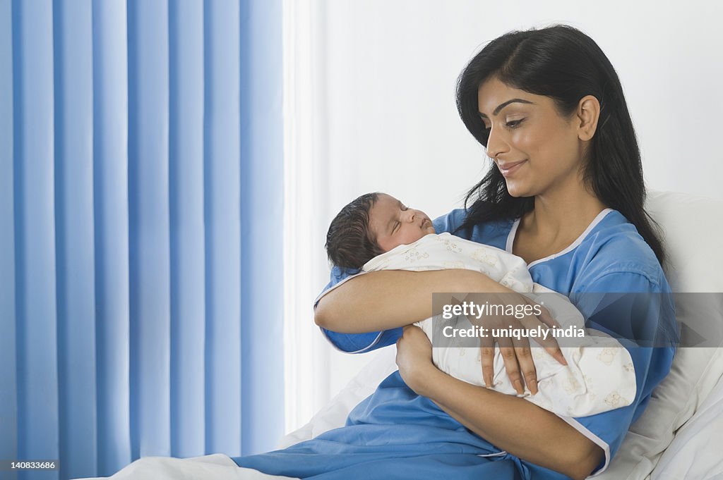 Woman looking at her baby on the bed