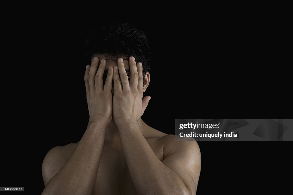 Close-up of a man hiding his face with his hands