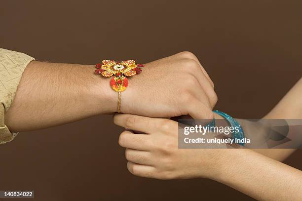 woman tying rakhi on the wrist of her brother - raksha bandhan stock pictures, royalty-free photos & images