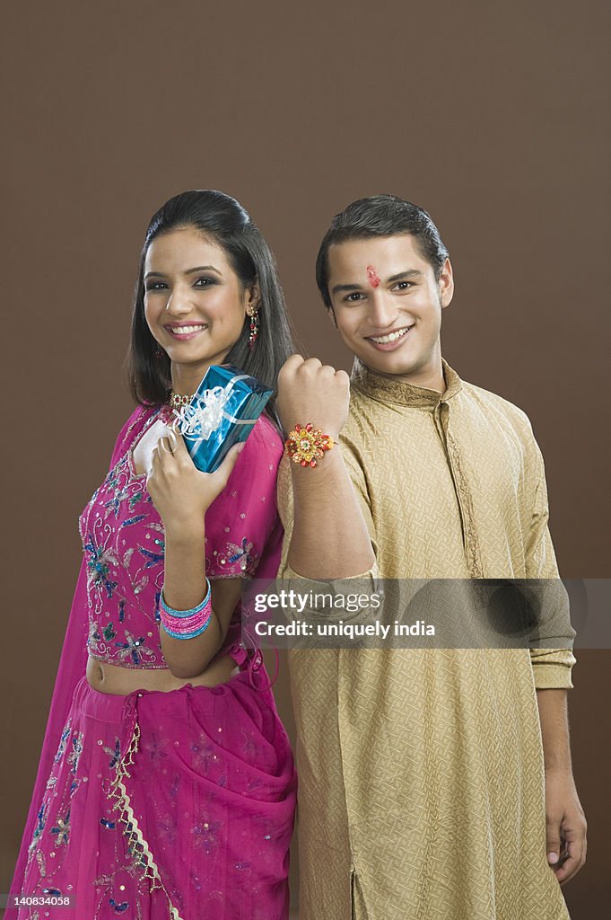 Man showing his rakhi with his sister showing her present