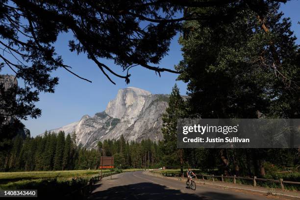 Yosemite National Park visitor rides a bicycle near Half Dome on July 12, 2022 in Yosemite Ntl Park, California. Firefighters continue to battle the...