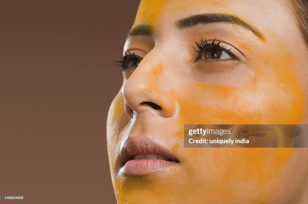 Close-up of a woman with turmeric on her face
