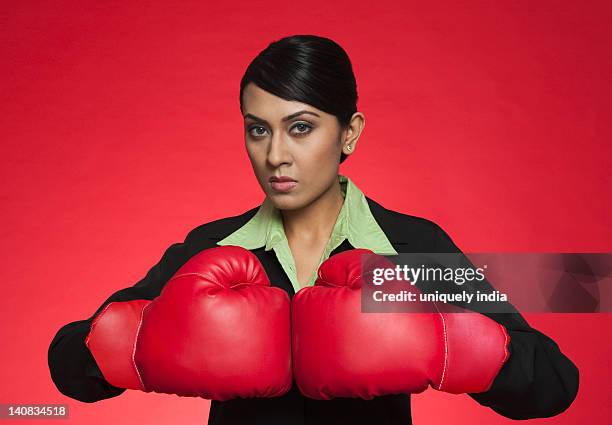 portrait of a businesswoman wearing boxing gloves - boxing glove coloured background stock pictures, royalty-free photos & images