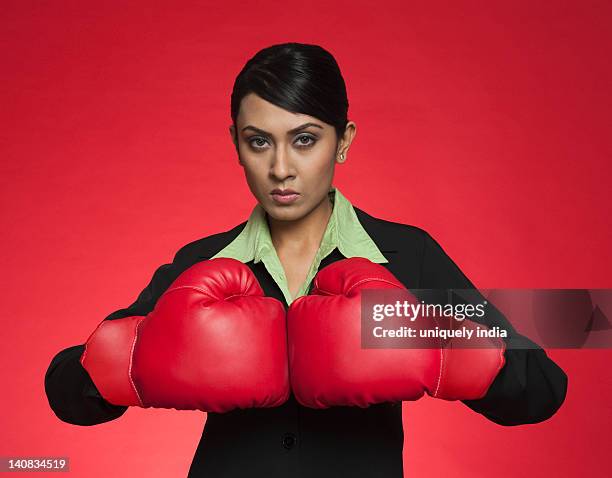 portrait of a businesswoman wearing boxing gloves - boxing glove coloured background stock pictures, royalty-free photos & images