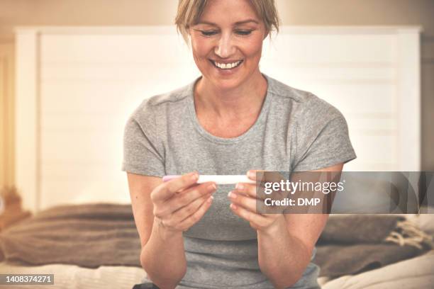 excited mature woman holding positive pregnancy test. expecting ivf mother anticipating baby, motherhood, parenthood. fertility hormone urine hcg stick and successful in vitro fertilization treatment - zwangerschapstest stockfoto's en -beelden