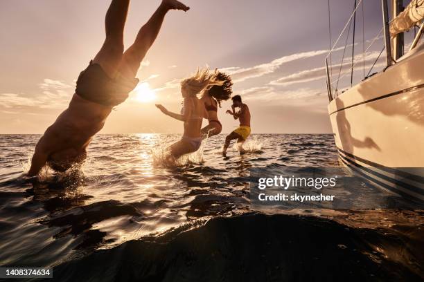 carefree people jumping into sea from boat at sunset. - croatia coast imagens e fotografias de stock