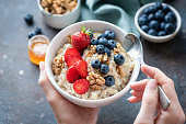 Oatmeal porridge bowl with berry fruits in female hands