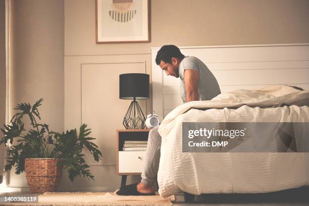 depressed, stressed man waking up early in morning, sitting in bed and thinking, feeling anxious, nervous and unprepared. suffering from mental disorder and feeling lost, confused, lonely, detached - dust dark bildbanksfoton och bilder