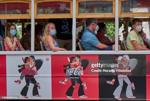 Mask-clad tourists ride by Praça Camoes on a Line 28 tram displaying Coca-Cola ads as temperature rises to 36º Celsius on July 12, 2022 in Lisbon,...