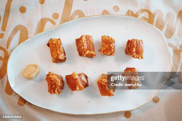 directly above crispy roasted pork belly on a white plate - schweinebauch stock-fotos und bilder
