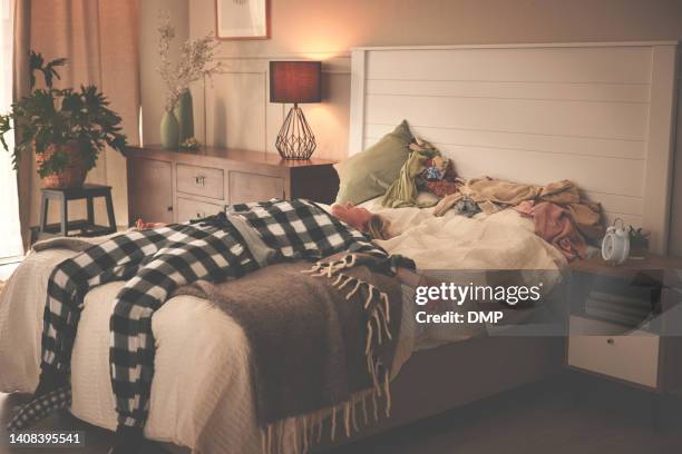mujer cansada en pijama acostada en su cama en un dormitorio moderno. mujer adormecida que lucha por levantarse por la mañana con una cama desordenada sin hacer. persona agotada mentalmente agotada que tiene problemas para despertarse - monday fotografías e imágenes de stock