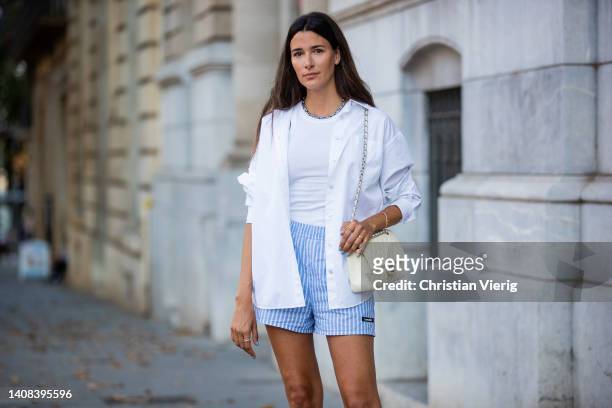 Paula Nata is seen wearing blue white striped Shorts by Lovechild, white button shirt shirt Arket, Tank top Toteme, Shoes Roger Vivier, creme white...