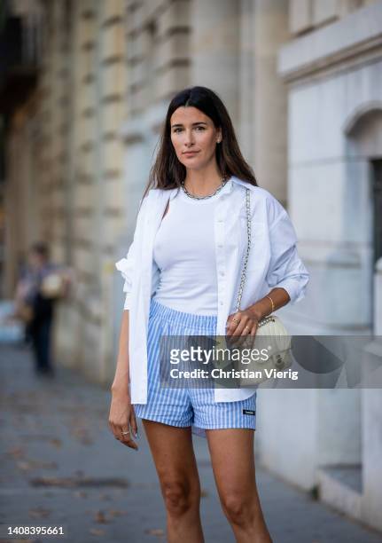 Paula Nata is seen wearing blue white striped Shorts by Lovechild, white button shirt shirt Arket, Tank top Toteme, Shoes Roger Vivier, creme white...