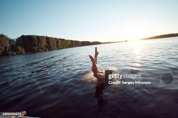 young woman jumping to open water from yacht at sunset - sun deck stock pictures, royalty-free photos & images
