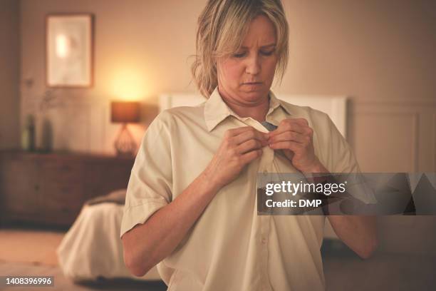 mature woman dressing and putting on fresh clothing while preparing for an interview. one female getting dressed and buttoning her shirt in the bedroom. freshening up and getting ready for work - knäppa knappar bildbanksfoton och bilder