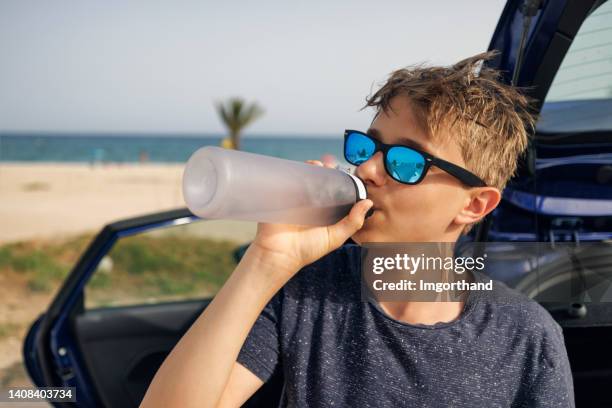 teenager drinking water from reusable bottle. - mirrored sunglasses stock pictures, royalty-free photos & images