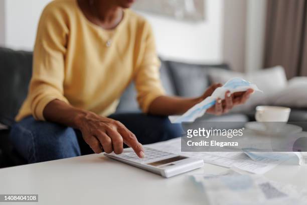 close up of a mid adult woman checking her energy bills at home, sitting in her living room. she has a worried expression - utility bill stockfoto's en -beelden
