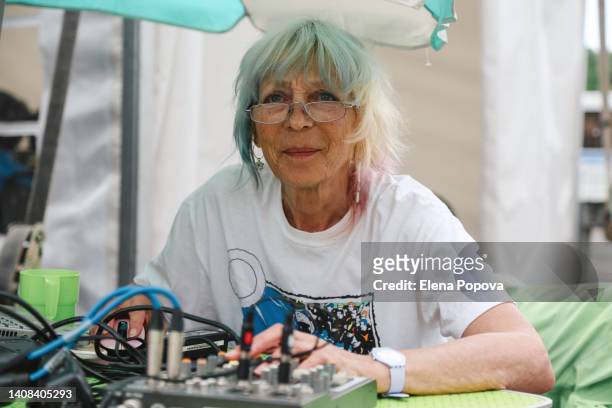 fashionable confidence senior woman with colored pink hair working dj mixing outdoor - dj summer stock-fotos und bilder