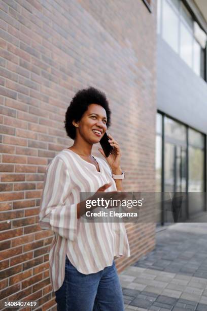 mid adult black woman using her smart phone on the street - brick phone stock pictures, royalty-free photos & images