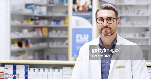 portrait of confident male pharmacist in a drugstore. caucasian healthcare professional in a pharmacy looking at the camera. portrait of a doctor standing in a clinic alone wearing a white coat - doctor lab coat bildbanksfoton och bilder