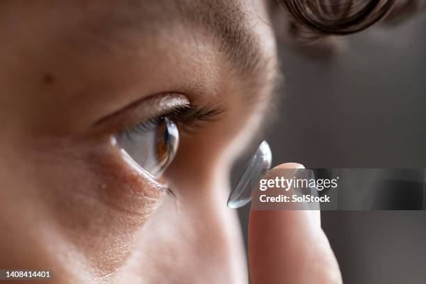 close up of young male adult putting in contact lens - inserts stock pictures, royalty-free photos & images