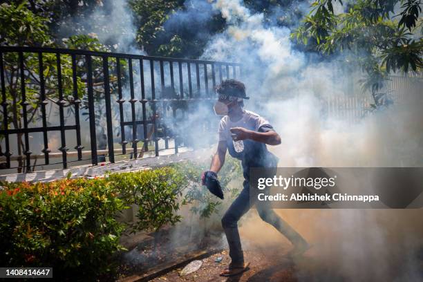 Protestor runs for cover from a tear gas canister fired by army personnel during a protest seeking the ouster of Sri Lanka's Prime Minister Ranil...