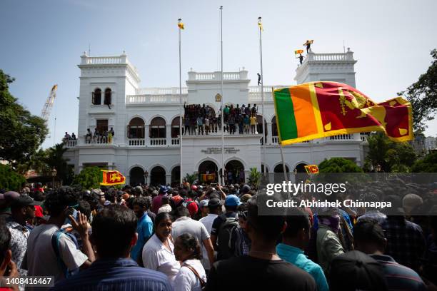 Protestors wave flags and chant slogans after taking control of the Prime Ministers office compound during a protest seeking the ouster of Sri...