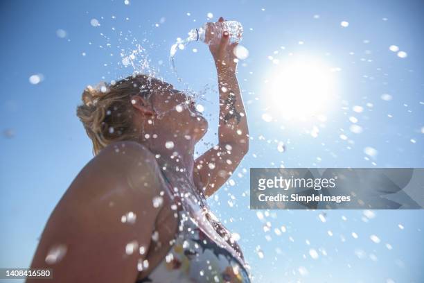 a young woman cools down with cold water during the summer heat. - calor fotografías e imágenes de stock