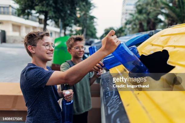 kids putting plastic bottles into plastic garbage container - kid throwing stock pictures, royalty-free photos & images