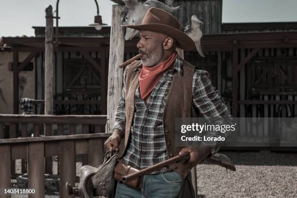 handsome black cowboy in an authentic wild west setting - handsome cowboy stock pictures, royalty-free photos & images