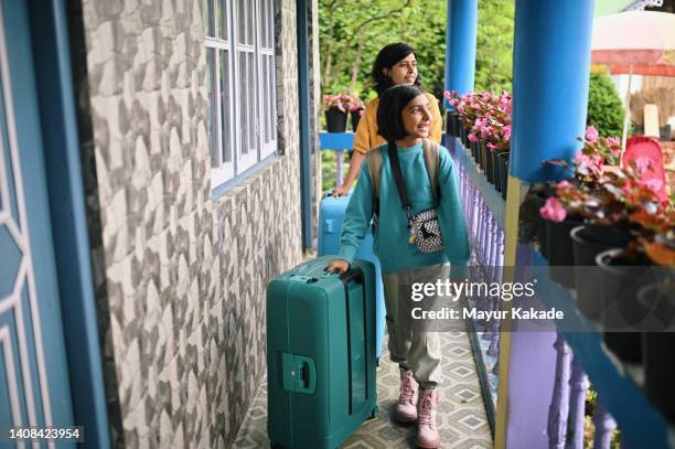 mother and daughter carrying their luggage bags - indian arrival stock pictures, royalty-free photos & images