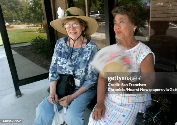 Nipa Wong fans herself to keep cool while waiting for a bus with her friend Mary Ellen Hankins at the senior center in Concord, Calif. On Thursday,...