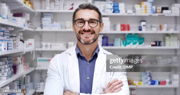 mature man working in a pharmacy. portrait of a confident smiling pharmaceutical manager and healthcare worker standing with his arms crossed ready to assist customers with medication in a chemist - monacle glasses stock pictures, royalty-free photos & images