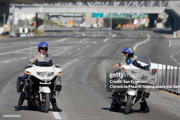 Officers Franco Jarquin and Albert Liu wait at the toll plaza top escort the first group of cars across the bridge after construction crews finished...