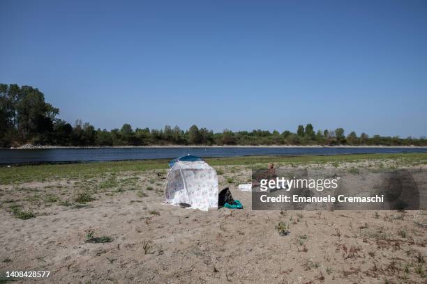 Two people sunbathe on the dry riverbed at the confluence between Po and Ticino rivers, next to Ponte Della Becca , on July 13, 2022 in Linarolo,...