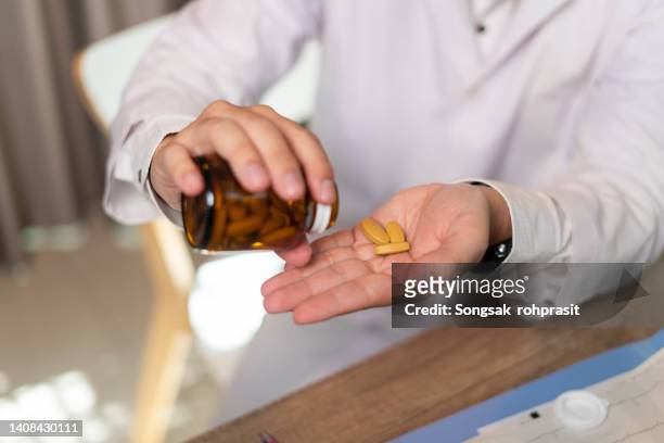man hand taking medicine - nutritional supplement fotografías e imágenes de stock