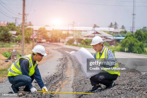 engineer worker making measuring with equipment at construction site during road works. - road construction fotografías e imágenes de stock