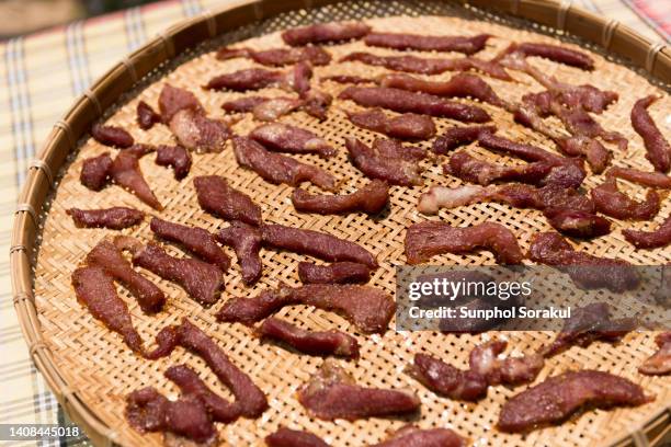 slices of beef being salted and dried on a bamboo tray in thailand - beef jerky stock-fotos und bilder